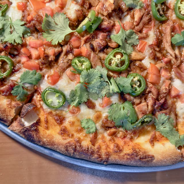 Scorpio pizza with chile-braised chicken, sliced fresh jalapeño, diced tomato, and cilantro